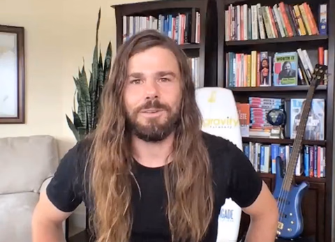 Dan Price speaking at the 2021 Float Conference, seated in front of a Gravity Payments-branded office chair