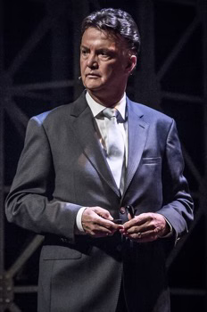 Louis van Gaal on stage at a public appearance in a formal suit
